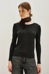 Remera de viscosa en color beige, de manga larga con detalle de frunces en los hombros y un pronunciado escote en la espalda con tira horizontal.