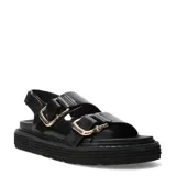 Sandalias de plataforma plana Miss Carol Milan, color negro, con dos tiras anchas en el empeine provistas de grandes hebillas metálicas doradas y tira ajustable en el talón.