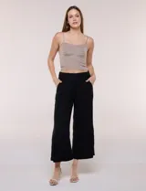Pantalón crop de lino y rayón, con diseño wide leg de corte holgado, estampado tropical de hojas en tonos verde, azul y marrón sobre fondo blanco. Cuenta con pretina trasera elastizada y bolsillos delanteros.