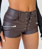 Short de cuero sintético color bordó, con diseño de cordones cruzados en la parte frontal y bolsillos laterales con cierre metálico.