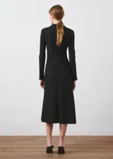 Vestido midi negro de manga larga, con cuello alto drapeado y corte estructurado en la cintura, falda acampanada de caída suave.