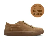 Zapatilla casual de cuero gamuzado en color marrón, con cordones al tono y suela de goma texturizada. Presenta costuras reforzadas visibles y un diseño de corte bajo.