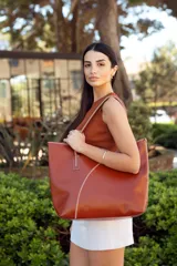 Bolso tote de cuero color marrón con costuras blancas a contraste. Tiene doble asa de hombro y diseño minimalista.
