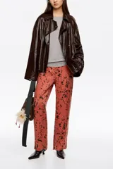 Pantalón de tiro medio y corte recto, con diseño estampado de manchas oscuras sobre base rojiza. Cuenta con cierre frontal de cremallera y corchete, bolsillos laterales y bolsillos traseros de vivo.