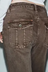 Jeans de tiro bajo con diseño bootcut y acabado flare en el bajo. Cuenta con cinco bolsillos, trabillas para cinturón y cierre frontal con cremallera y botón metálico.