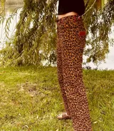 Pantalón de jean con estampado animal print en tonos beige y negro, de corte ancho y tiro medio. Presenta detalles de cuero bordó en la pretina y los bolsillos.