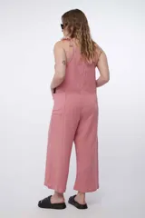Mono largo de algodón color beige, de corte holgado, con escote recto y tirantes ajustables mediante lazos en los hombros. Cuenta con bolsillos laterales y perneras amplias tipo culotte.