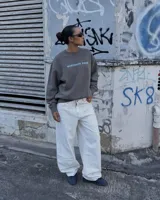 Buzo gris oscuro con efecto acid wash, corte regular fit y cuello redondo. Presenta una estampa grande en la espalda con diseño de calavera, el texto "Kaboa" y detalles de fechas de tour en tonos claros.