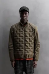 Cazadora deportiva acolchada color verde oscuro, con cuello alto y cierre frontal con cremallera. Cuenta con bolsillos laterales con cremallera oculta y un bolsillo interior.