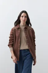 Sobrecamisa de gamuza color marrón con bordados decorativos estilo western en la zona de los hombros y cierre frontal con botones metálicos.