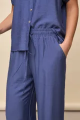 Pantalón gris de corte amplio y silueta fluida, con cintura elástica y cordón ajustable.