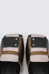 Mules de cuero color beige con detalles en marrón y suela de madera.