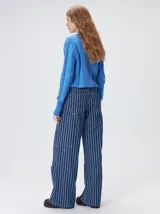 Sweater de punto con diseño de rayas verticales en tonos negro y gris oscuro. Presenta cuello alto tipo polera, mangas largas con puños ajustados y ruedo elástico. Incluye un pequeño bordado en color rojo en el pecho.