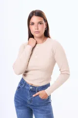 Remera de manga larga en tejido de punto acanalado, color blanco, con cuello redondo y cierre frontal parcial con botones.