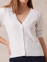 Cárdigan blanco tejido con escote en V, abertura frontal con botones y mangas cortas abullonadas con puño.