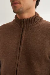 Campera tejida color marrón claro con cierre delantero, cuello alto y bolsillos delanteros. Tejida en 100% lana fina sin teñir.