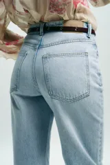 Jeans de tiro alto con corte de pierna recta y diseño de cinco bolsillos. Confeccionados en tejido denim rígido de lavado claro, incluyen un cinturón fino de cuero en tono marrón.