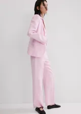 Blazer de lino color rosado, de diseño recto con cuello en pico y solapas con muesca. Cuenta con manga larga, dos bolsillos de ribete delanteros y cierre frontal de un botón.
