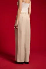 Pantalón ancho de lyocell color beige con pinzas en la parte delantera, tiro alto y un cinturón delgado con hebilla redonda metálica.