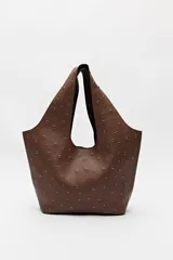 Bolso tipo tote negro de cuero sintético con micro tachas metálicas plateadas. Tiene asas integradas para llevar al hombro.