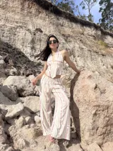 Pantalón ancho de tiro alto, color crema con estampado vertical de líneas irregulares en tono rosado/malva. Presenta cintura elástica.