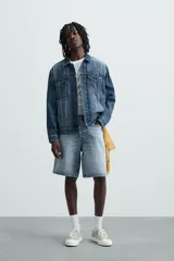 Bermuda de denim de algodón, color verde claro lavado, de corte recto y tiro medio. Presenta cinco bolsillos y cierre frontal con cremallera y botón.