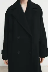 Abrigo largo de corte oversize con cuello de solapa, manga larga y cierre frontal cruzado con botones. Cuenta con bolsillos delanteros.