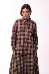 Camisa de manga larga con estampado de cuadros tartán en tonos marrones y beige, con cuello clásico y cierre frontal de botones.