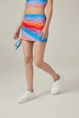 Minifalda con estampado degradado en tonos azul, lila, naranja y rojo. Presenta frunces laterales con cordones ajustables.