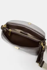 Bolso alargado color marrón con pespuntes en contraste. Tiene un bolsillo exterior con botón imantado, doble asa bandolera ajustable (una de tela), compartimento interior con cremallera y cierre con solapa y clip metálico.