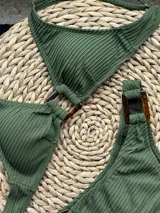 Conjunto de bikini marrón chocolate con tela acanalada. El corpiño es de triángulos fijos unidos por una argolla central y tiene breteles y lazo regulables en la espalda. La bombacha es vedetina con argollas de madera en las caderas.