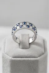 Anillo de plata 925 con diseño de banda ancha, decorado con una hilera central de circonias blancas en corte baguette y dos hileras laterales de circonias azules redondas.