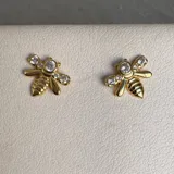 Par de aros dorados con forma de abeja y pequeños brillantes incrustados.