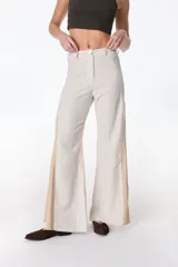 Pantalón de pierna ancha confeccionado en lino, con diseño bicolor que incorpora paneles laterales en tono contrastante para mayor amplitud. Presenta cierre frontal con botón y trabillas para cinturón.