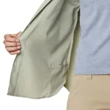 Camisa de manga larga Columbia, color verde claro, con cuello clásico, cierre frontal de botones y dos bolsillos frontales en el pecho. Presenta un diseño funcional con ventilación y tecnología de protección solar.
