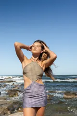 Vestido corto de estilo cut-out con escote halter, confeccionado en lycra ecofriendly con estampado geométrico en tonos verdes y azules.