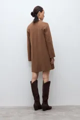 Sacón azul marino de corte largo, con cuello solapa, cierre frontal de dos botones dorados y bolsillos de parche.