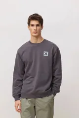 Buzo de cuello redondo, manga larga, color gris oscuro con un pequeño estampado de una cruz en el pecho.