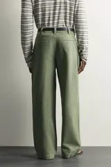 Pantalón chino baggy fit color verde militar, confeccionado en denim de algodón rígido, con corte holgado, tiro medio y pliegues frontales. Presenta bolsillos laterales y cierre frontal con cremallera y botón, con efecto lavado.