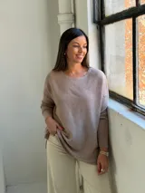 Sweater de punto en color visón, con cuello redondo, manga larga y diseño holgado con aberturas laterales en el ruedo.