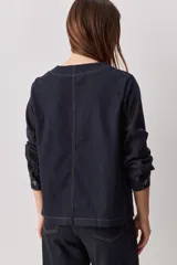 Sobrecamisa de jean azul oscuro, de calce relajado, escote en V, bolsillos delanteros aplicados, cierre frontal con botones metálicos y pespuntes en contraste.