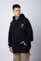 Buzo tipo canguro de corte oversize, color blanco, con capucha y cordones ajustables. Presenta un pequeño estampado de una rosa roja en el pecho y un bolsillo frontal tipo canguro.