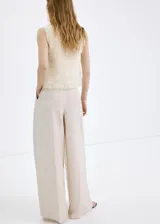 Top de punto fino color beige, con diseño recto, cuello redondo, tirantes anchos y detalles fruncidos con capas semitransparentes.