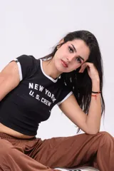 Baby tee negra estilo ringer, con ribetes blancos en el cuello y las mangas, y estampado frontal con la inscripción "NEW YORK U.S. CREW".