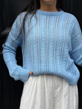 Sweater color crema tejido con diseño en ochos y cuello redondo.