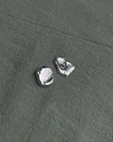 Aros tipo caravanas de diseño orgánico con forma irregular y textura rugosa, con acabado metálico brillante.