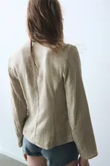 Blazer de cuello redondo con escote en pico, manga larga y cierre frontal con botones metálicos. Presenta falsos bolsillos con solapa en el delantero y un diseño estructurado.