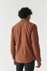 Camisa rústica lisa de manga larga color verde militar, con cuello clásico y dos bolsillos frontales con solapa.
