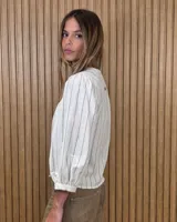 Camisa de cuello redondo y manga larga abullonada, con diseño a rayas en tonos rosado y blanco.