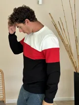Buzo de cuello redondo con diseño de bloques de color horizontal en blanco, rojo y negro. Presenta mangas largas con puños elásticos y terminación en el ruedo con elástico.